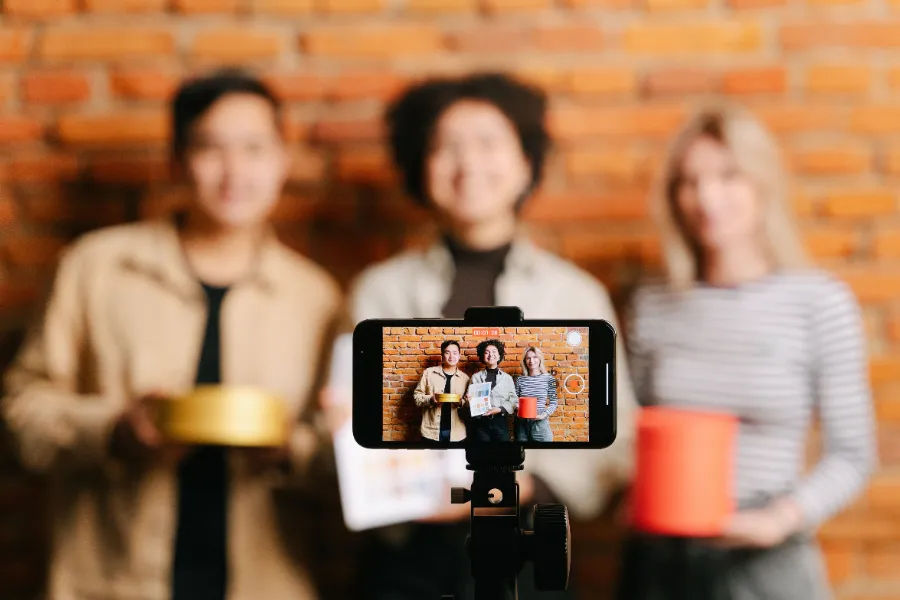 Trois créateurs de contenu tournant une vidéo sponsorisée avec un smartphone sur trépied